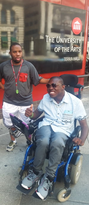 Two classmates outside Temple University Student Center, one using wheelchair