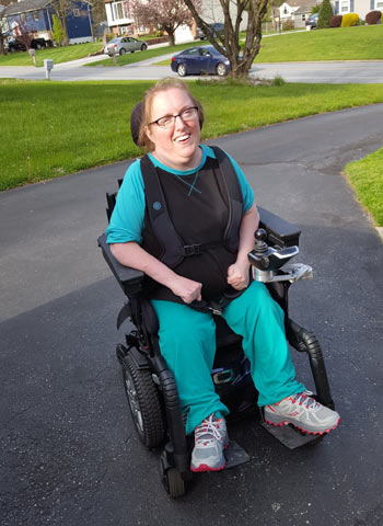 Holly, using her wheelchair in a suburban driveway