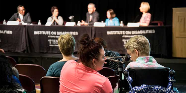 Two women talking in audience at Institute on Disabilties panel discussion