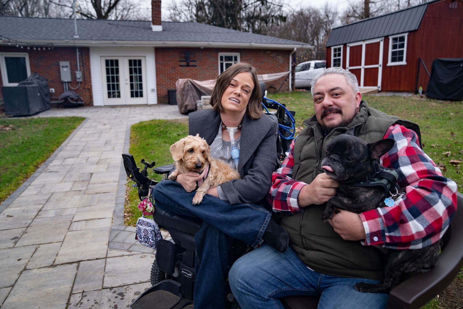 Josie outdoors with a man, each holding a small dog in their laps