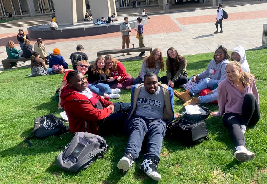 students relax together on lawn near Temple's bell tower