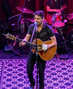 Isaac Merz performing on stage with guitar