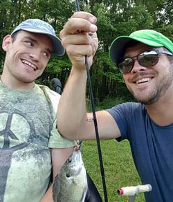 Robert with another man who holds a fishing rod with a fish attached