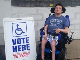 Robert next to a sign that says Vote Here