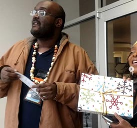 William stands next to a smiling woman who holds a gift