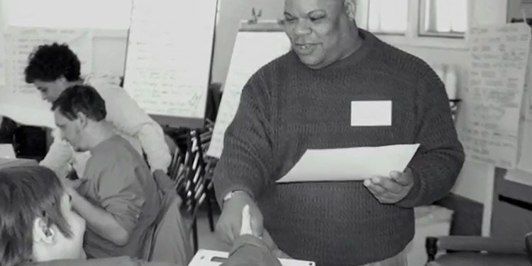 Black and white photo of Roland Johnson working with others in an office