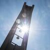 Temple University's Bell Tower against a blue sky, rays of light advancing through