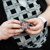 Person with cherry red painted nails and wearing a black and white outfit holds a C2P2 pin