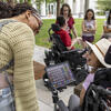 Small and lively group chat together outdoors on campus, some using augmentative and alternative communication