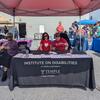 Eva and Shirley, wearing red shirts, at event table covered with information sheets and giveaway items