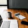 laptop, notepad, pen, and coffee on a wooden table