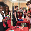 Two students review information and giveaways as a staff member speaks with them