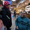 Rodney, a Black man using a wheelchair, laughs with another shopper in Reading Terminal Market