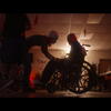 In silhouette, a person leans down to Fred, who uses a wheelchair