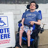 Robert rolls up to his polling place using his power chair. The sign says, Vote Here Accessible Entrance