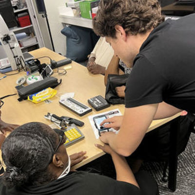 A staff member demonstrates assistive tech at a table with others