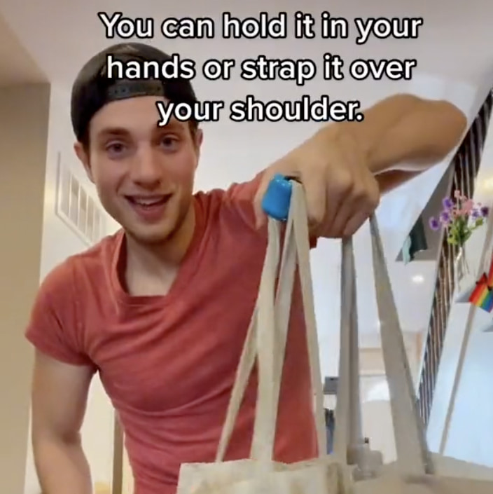 Tom holds up plastic grocery bags using a broad smooth plastic handle. Text: You can hold it in your hands or strap it over your shoulder